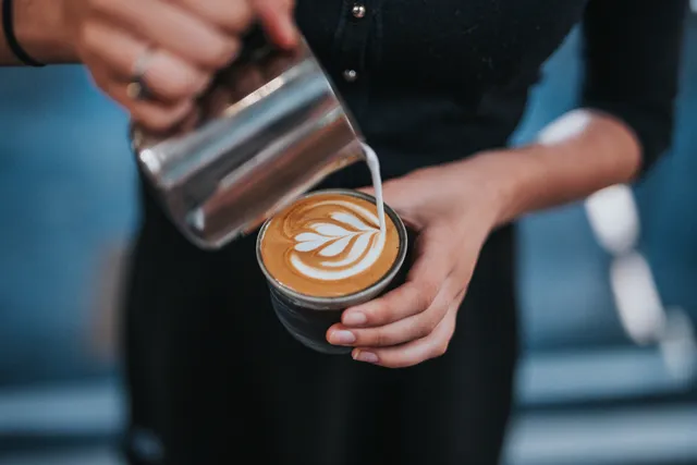 Picture of a barista creating latte art in a cup of coffee